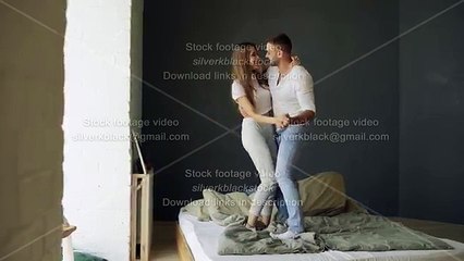 Young beautiful and loving couple dancing and kissing on bed in morning