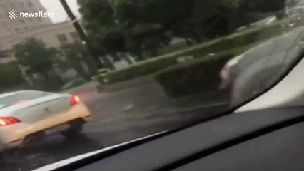 Convertible passengers use umbrellas to protect themselves from the rain