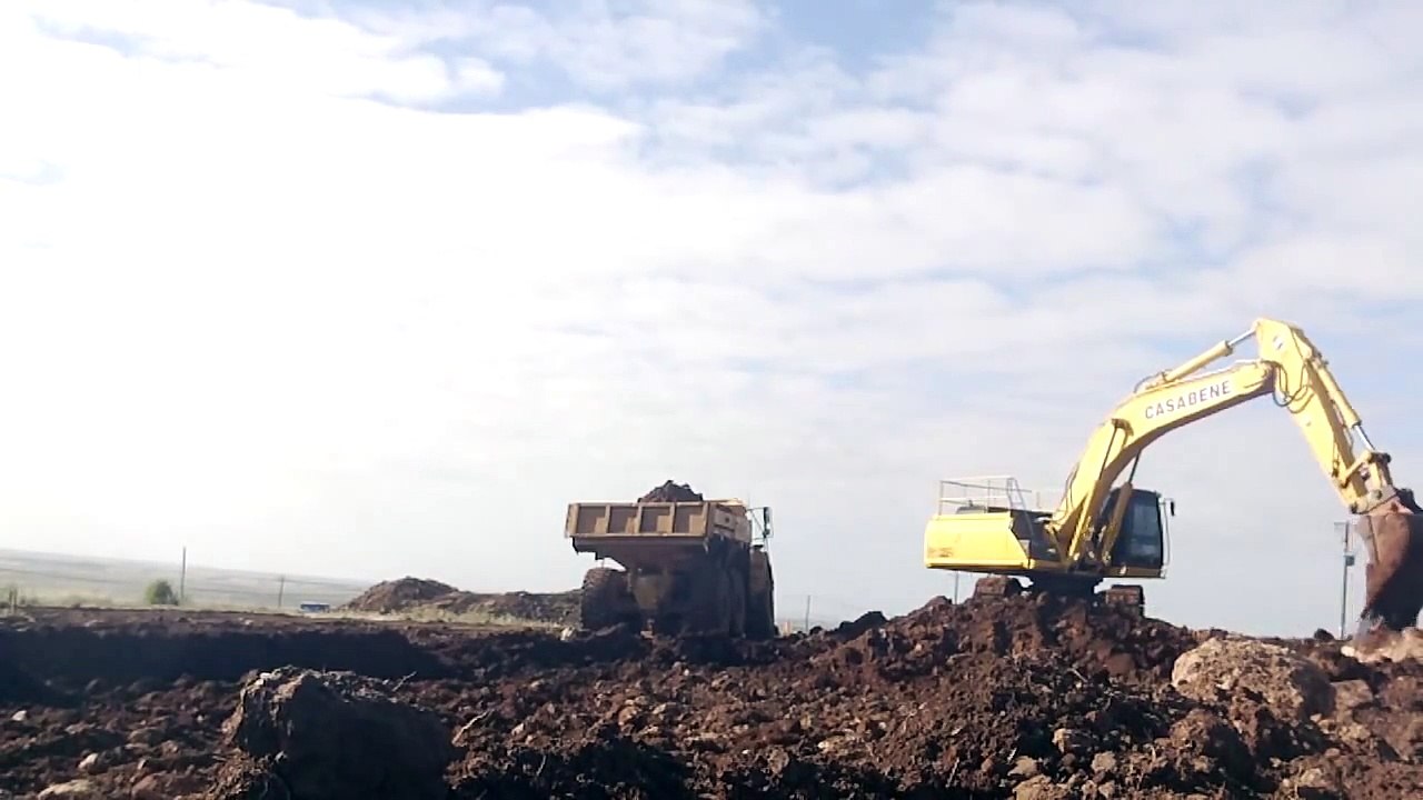 Excavator loading 3 articulated dump trucks.