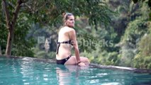 videoblocks-attractive-woman-sitting-on-the-edge-of-swimming-pool-and-relaxing-steadycam-