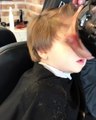 adorable enfant drôle s'endormir tandis que le coiffeur coupe ses cheveux