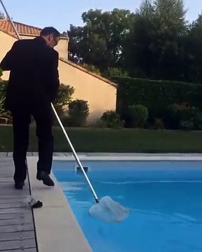 Un père de famille en costume poussé par son fils dans une piscine