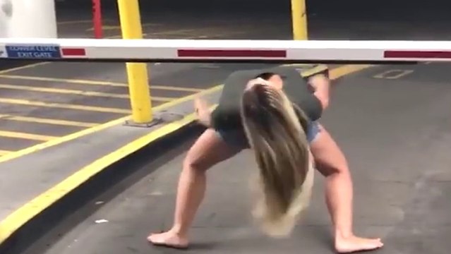 Une fille fait le jeu du limbo avec une barrière de parking
