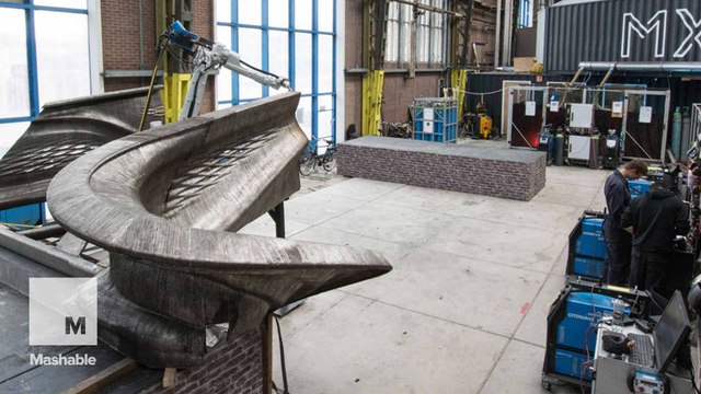 Industrial robots weave a metal bridge as they move in mid-air