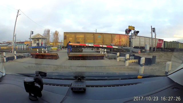 Un cycliste passe entre deux trains à un passage à niveau