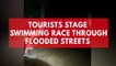 Tourists stage swimming race through flooded street