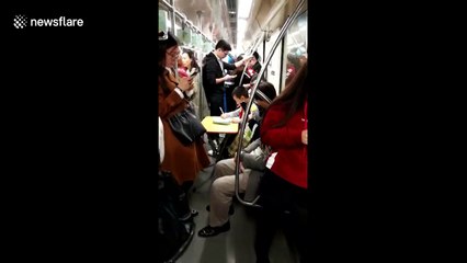 Boy does homework on carry-on folding table in subway carriage