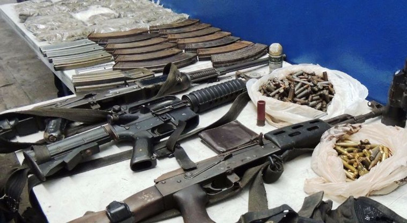 TRAS LAS REJAS TRES SUJESTOS  ARMADOS Y VESTIDOS DE MILITARES