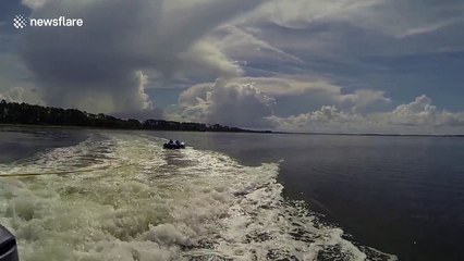 Dolphins jump in boat's wake while kids ride inflatable tube