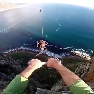 Un homme fait un saut pendulaire du haut d’une falaise puis saute dans le vide