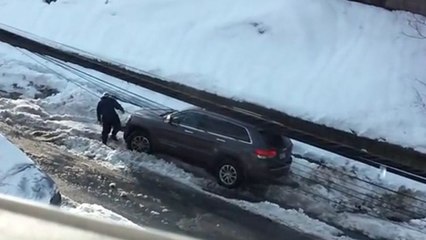 Un homme galère à sortir sa voiture à cause de la neige