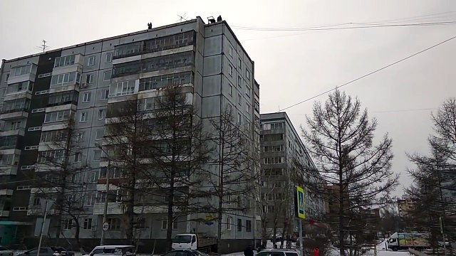 Ils chargent un camion en balançant de la marchandise du toit d’un immeuble en Russie