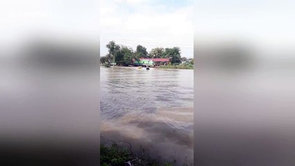 Father using jet ski to pull children on dingy during flood