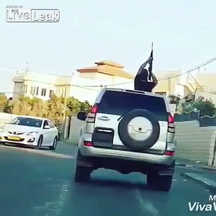 Arab holding gun out of sunroof in midst of a village in Israel
