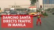 Dancing Filipino traffic cop in Santa Claus costume directs traffic in Manila