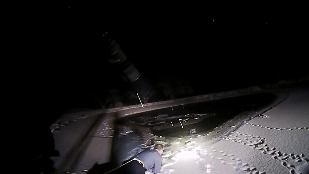 Police officer crawls across ice to rescue trapped dog