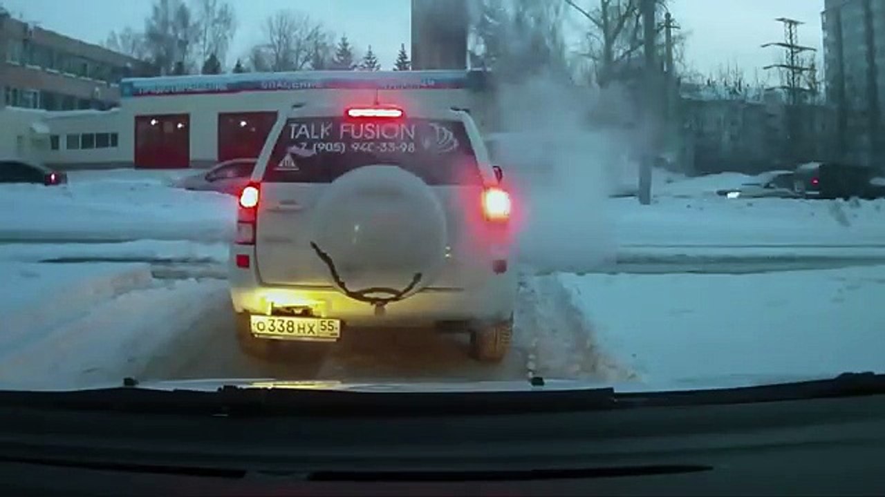 Un homme aide une vielle voiture à se désembourbé de la glace