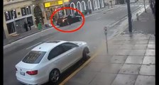 Un homme avec un bonnet du Père Noël tire sur une voiture en pleine rue.