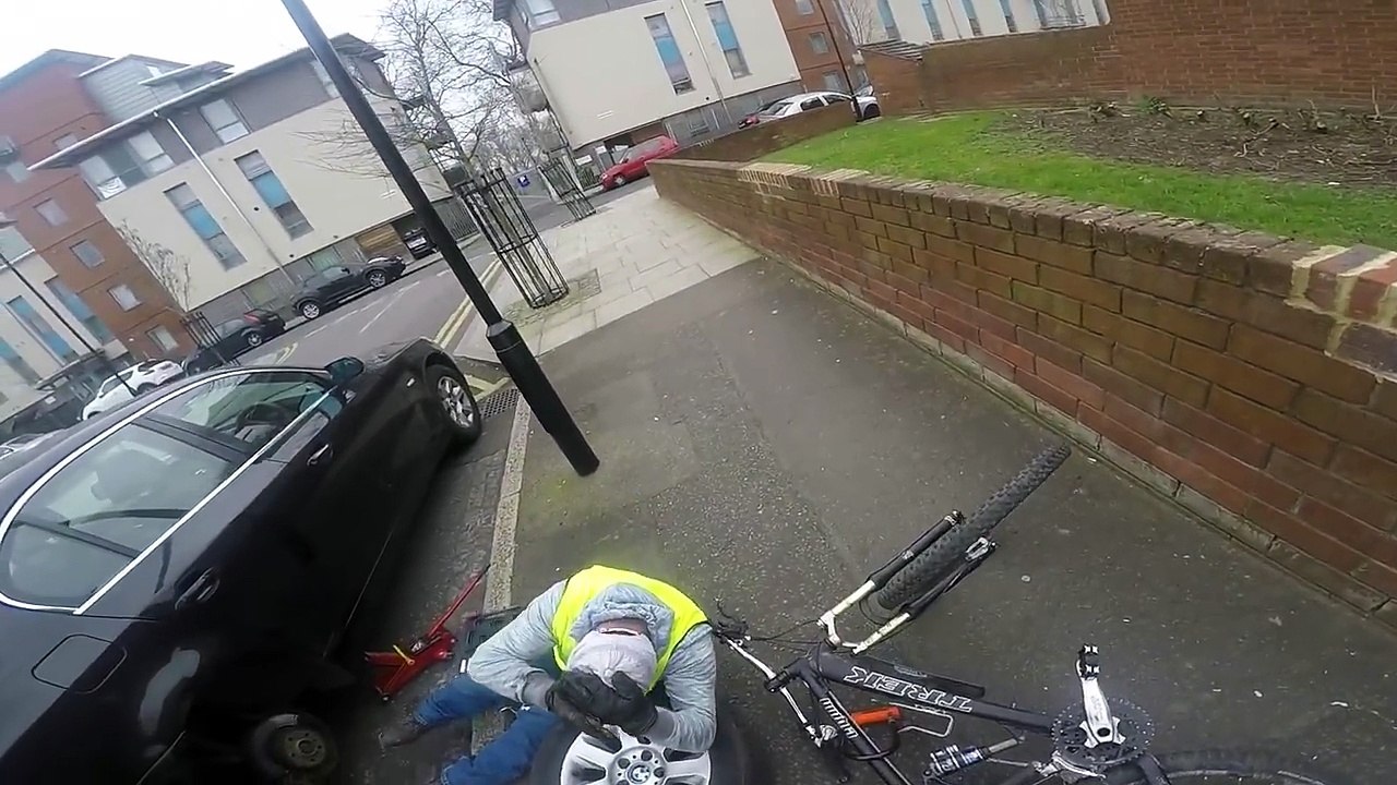 Ce cycliste tombe sur un homme en train de changer sa roue de voiture !