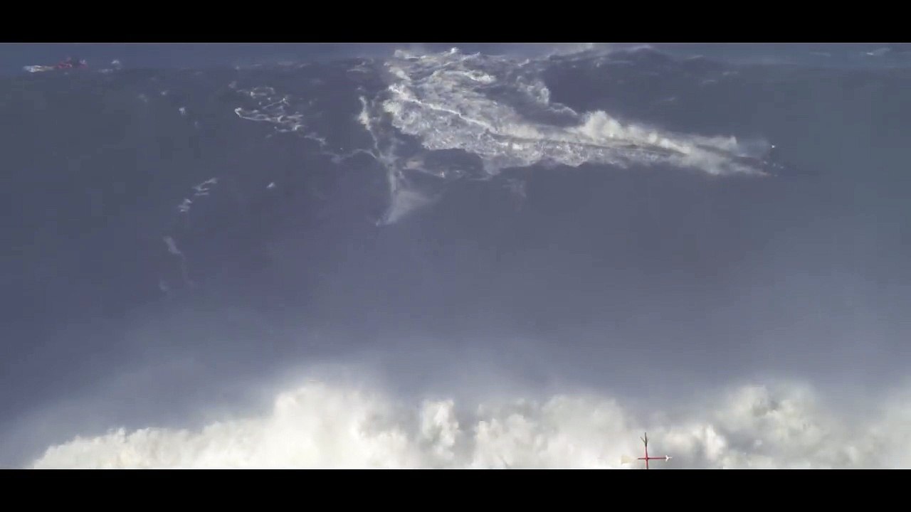 Un homme surfe l'une des plus haute vague du monde au Portugal