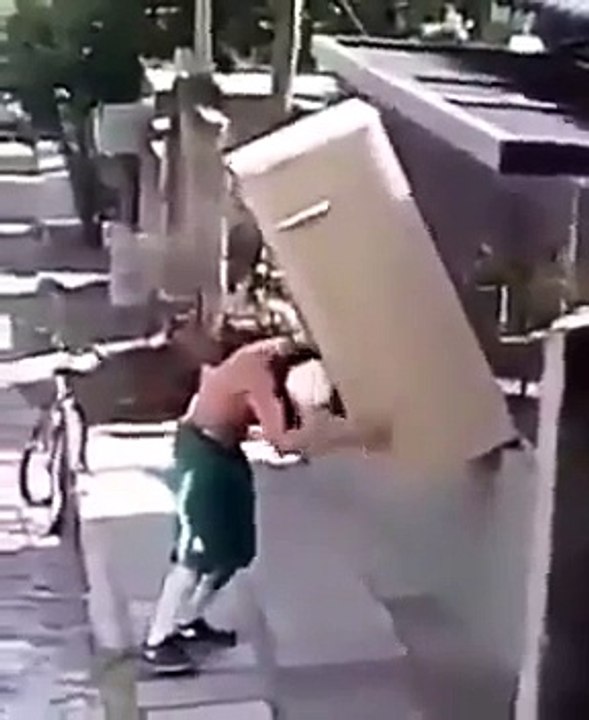Un homme transporte un frigo sur son épaule et à vélo