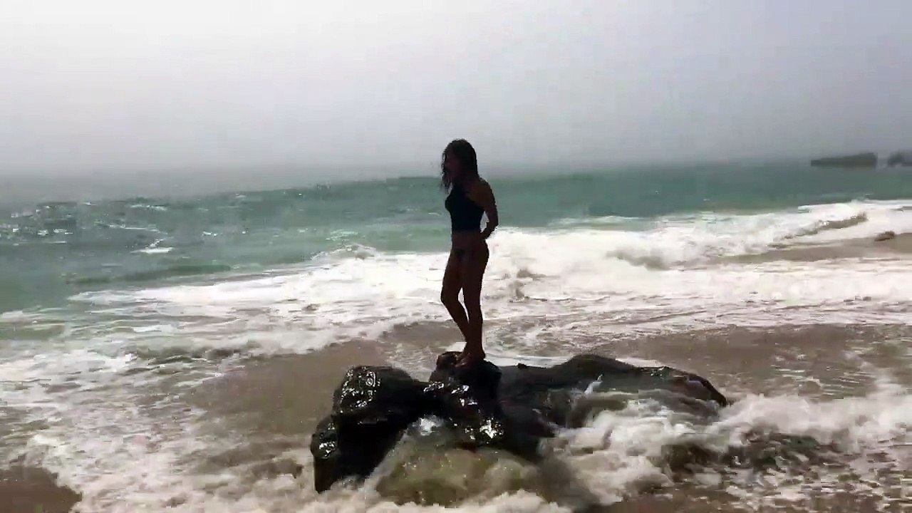 Une fille fait la belle sur un rocher en mer