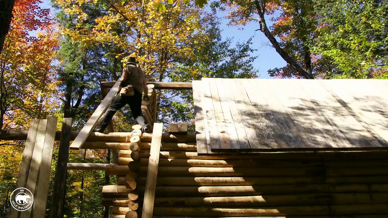 Un homme construit lui même sa maison dans les bois