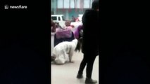 Woman crawls on all fours next to fiancé on busy street in China