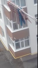 Une femme lave ses carreaux à l'extérieur au dessus du vide