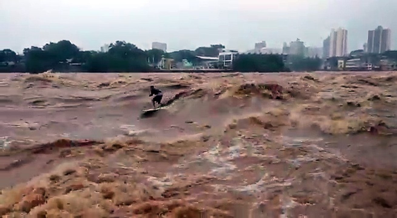 Ce surfeur ride prend les vagues d'un fleuve en...