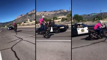 Un policier sort son arme et met en joue un motard qui fait un wheeling