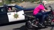 Un policier sort son arme pour un motard qui fait un wheeling sur la route