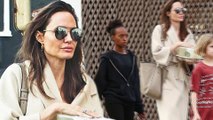 Angelina Jolie picks up iced tea as Vivienne and Zahara cart the bags on shopping trip.