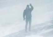 Bostonian Trudging Through Snow Waves to Camera During Blizzard
