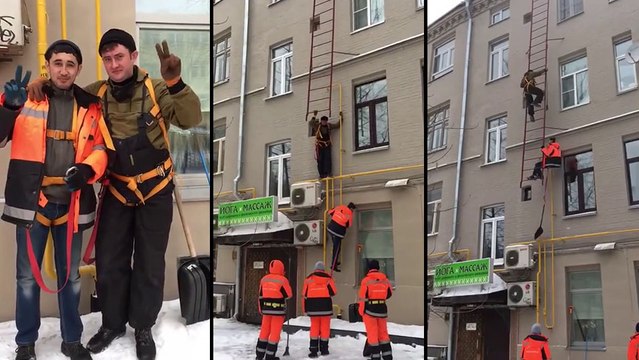 Deux ouvriers passent par une échelle de secours pour déneiger le toit d’un immeuble