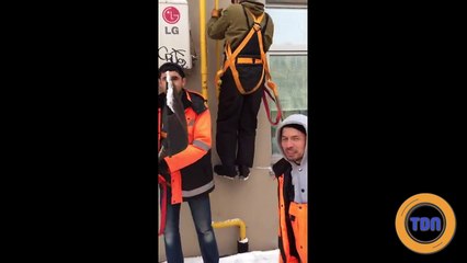 Deux ouvrier montent sur une échelle anti-incendie pour déneiger le toit d'un immeuble et chutent