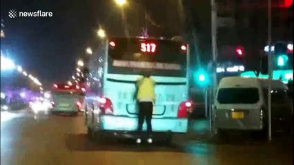 Man on roller skates holds on to back of moving bus