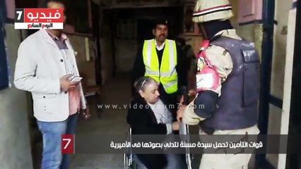 قوات التأمين تحمل سيدة مسنة لتدلى بصوتها فى الأميرية