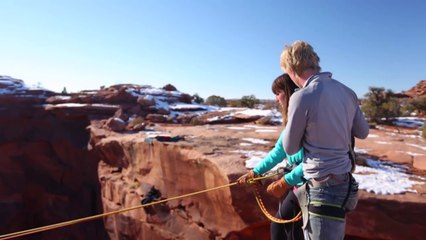Il pousse sa copine attachée à une corde  du haut de la falaise