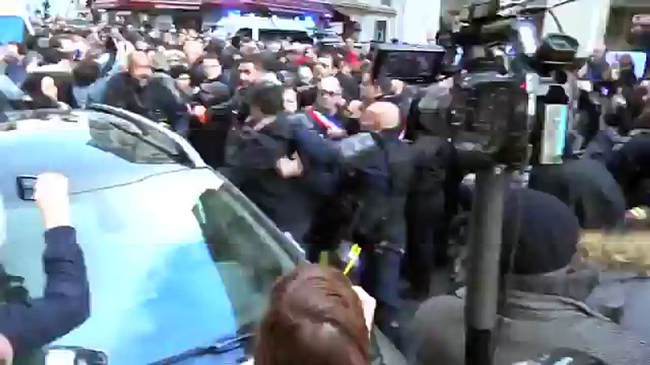 Un CRS pointe son arme sur un photographe