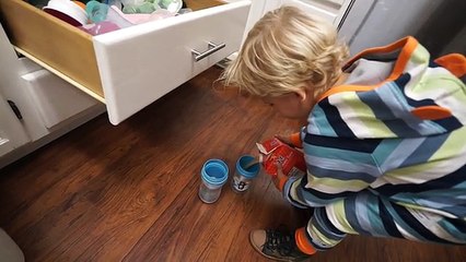 Un enfant de 3 ans prépare deux verres de jus de fruits