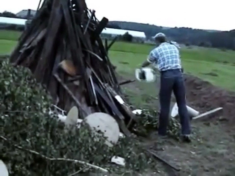 Un papi utilise de l'essence pour allumer un tas de bois