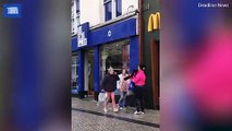 Dozens of people watch a brawl break out in front of McDonald's