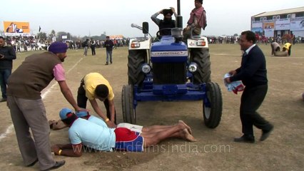 Tractor torture - men going under massive tractor wheels!