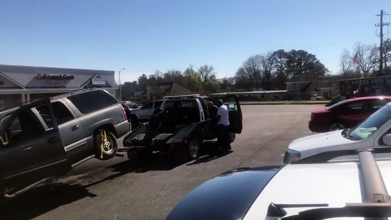 Un homme essaye désespérément d'avancer alors que sa voiture est en train de se faire remorquer