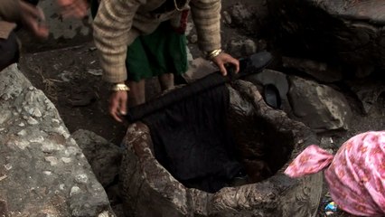 Women wash clothes with their feet in an old hollow tree log in India