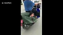 Man carries child in bag hanging on speeding motorcycle