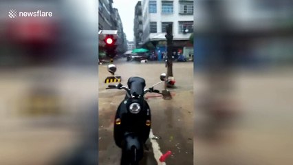 Watch a traffic light get swept down the street by flood waters in China