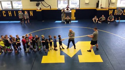 50 enfants tirent une corde contre un homme musclé