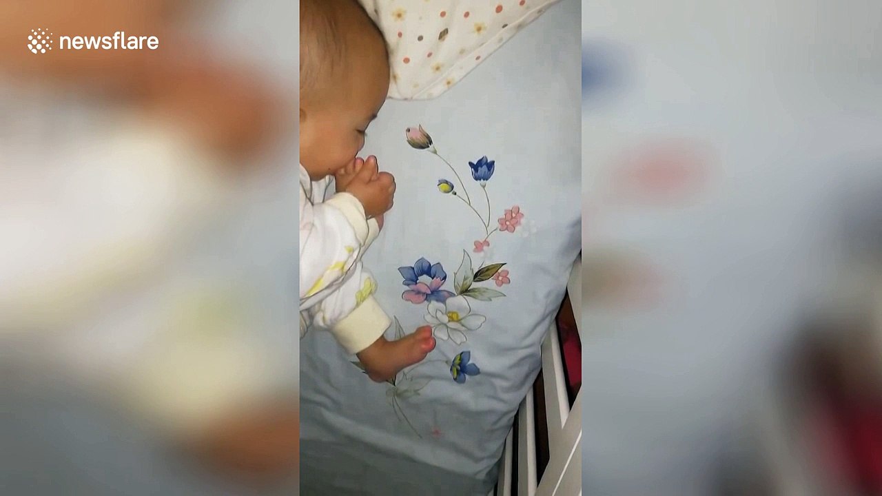 Adorable baby licks toes while sleeping